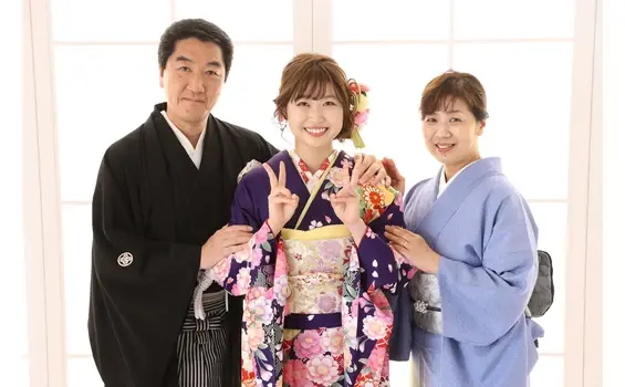 紫色の振袖姿の若い女性と両親