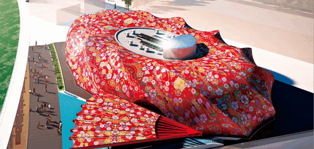 大阪万博のパビリオンの航空写真。大きなフリル状の花のような形をしており、鮮やかな赤い布で覆われ、着物を思わせる花柄が施されています。中央の円形の開放的な空間には座席と銀色のドームがあり、外側に向かって通路と扇風機が伸びています。.