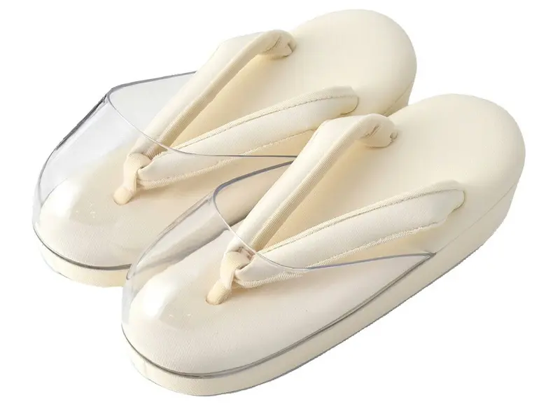 クリーム色の厚底と布製の鼻緒が特徴の伝統的な草履です。雨の日でも安心の透明プラスチックで保護されています。クラシックな要素を保ちながらもモダンなデザインは、着物との相性も抜群です。背景は白無地です。.