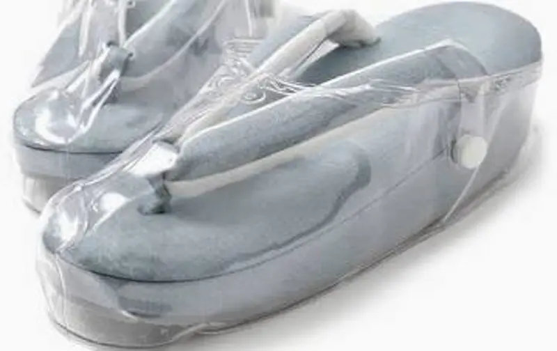 厚底の水色のスリッパで、サイドのスナップボタンで開閉する透明なプラスチック製カバーにすっぽり収まっている。.